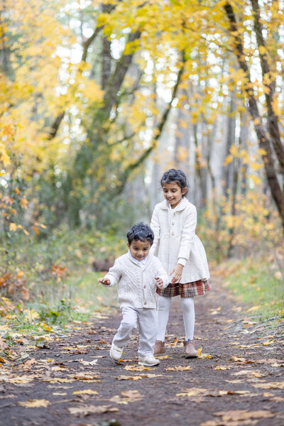 Siblings playfully run around during a fall photoshoot 