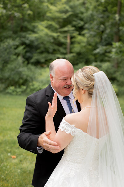 Father of the bride embraces his daughter after he sees her in her wedding dress