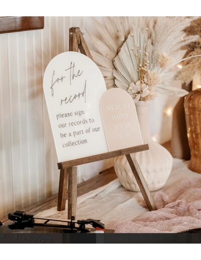 Two arched signs on an easel for a wedding guestbook.