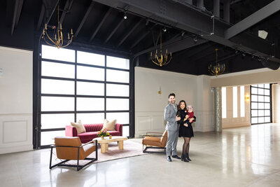 Edelcup family posed in front of finished Happy Hour space, highlighting lounge vignette amenity and natural lighting with chandelier detail
