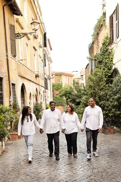 Family of four holding hands walking down the streets of Trastevere. Taken by Rome Family Photographer, Tricia Anne Photography