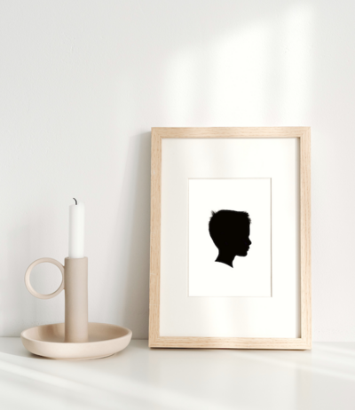 framed photo of child silhouette artwork next to candlestick