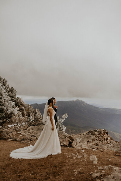 bride and groom standing in front of a lake