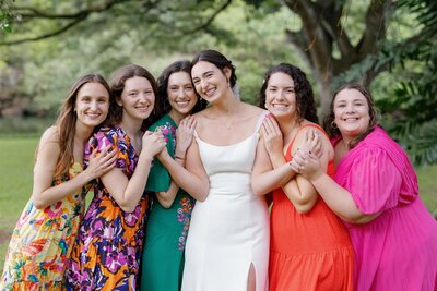 A newlywed in a wedding dress smiling with guests on either side of them 