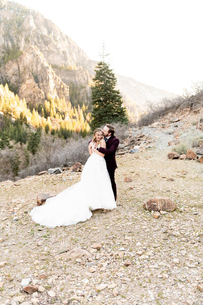 Bride and groom walking through the Arizona desert holding hands with mountains and cacti in the background.