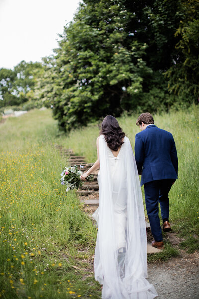couple walking up garden stairs with long veil