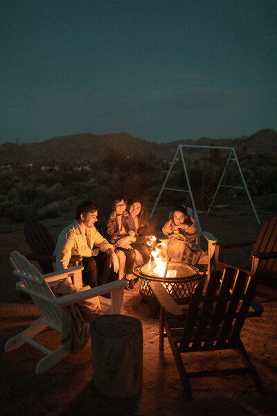 A family is enjoying a cozy night by a fire pit, sharing stories and laughter under the starry sky.