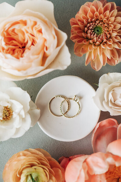 Two rings are surrounded by peach flowers by Lavish Floral Design. Photo by