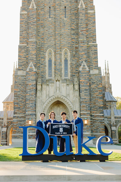 Group of college graduates in gown holding a banner during a portrait session.