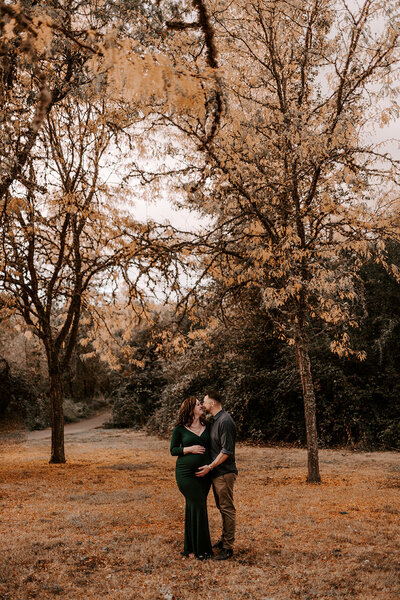 couple kissing and holding pregnant belly