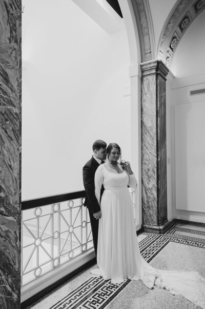 a bride and groom smiling together near a stained glass window