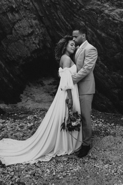 black& white. A holding her bouquet down at her side with  her right hand, whilie she holds herself against J's chest/chin. J holding onto A kissing her forehead