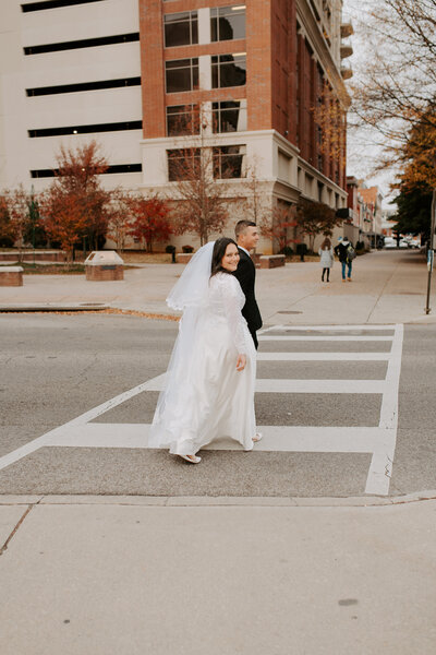 bride and groom walking across the street in downtown Roanoke after their elopement