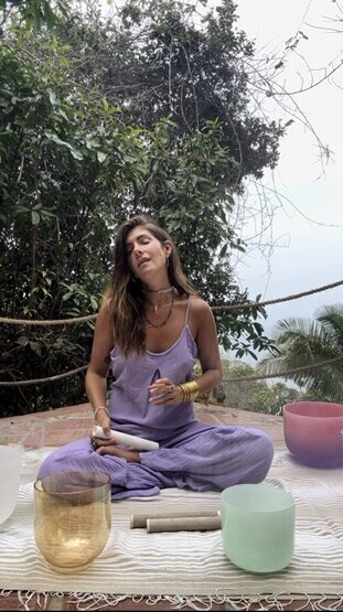 Leah Cavazzini leads a vocal sound healing session outdoors, blending her expertise in voice coaching with crystal singing bowls to help others unlock self-expression and emotional release.