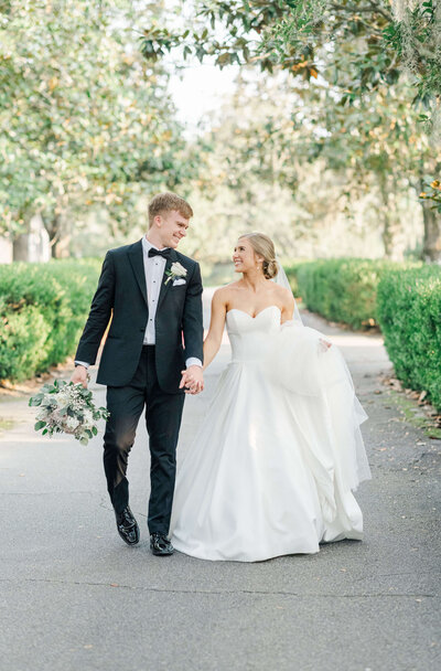 wedding couple smiling at eachother and walking toward wedding photographer