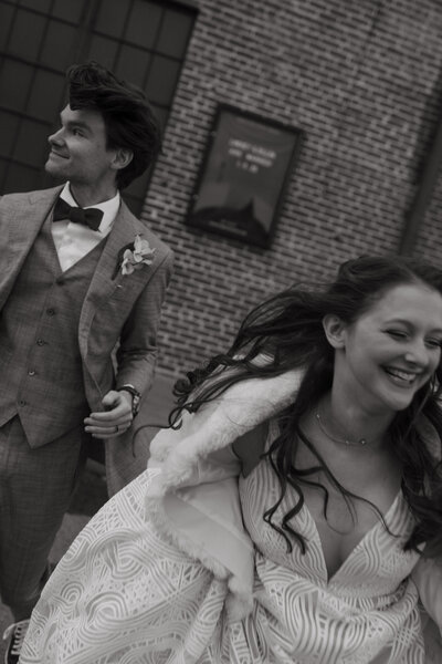 bride and groom running towards camera in black and white