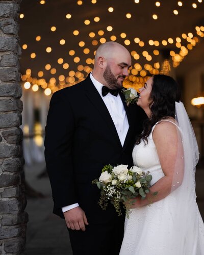 The bride and groom moments before a kiss under the string lights at The Sablewood in Schoharie, NY.
