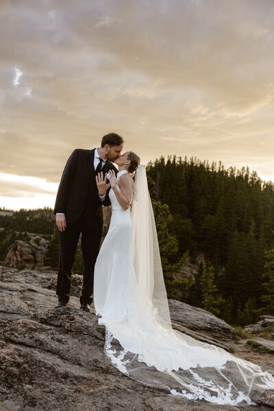 groom and bride kissing and showing off their wedding rings to their colorado elopement photographer