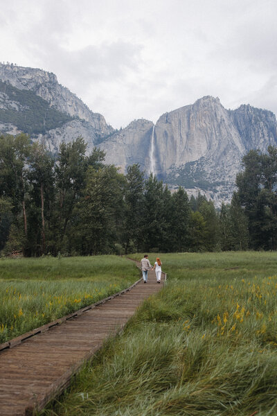 a couple holding hands walking through Yosemite Valley in California