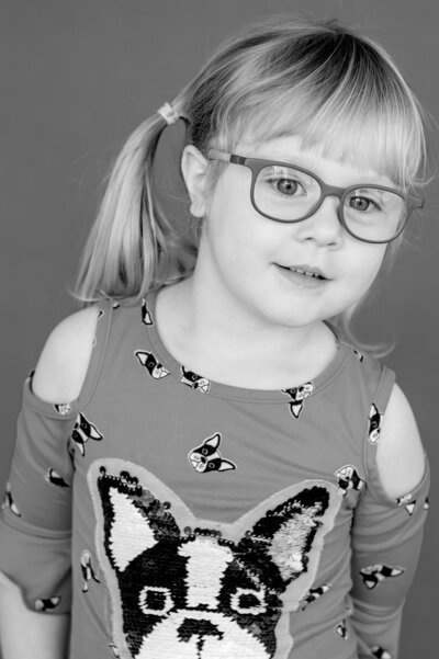 Preschool girl, wearing glassess looks just beyond the camera for her school photos