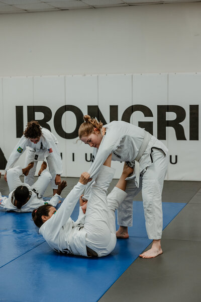 Two women drilling in gis in a jiu jitsu class in downtown Raleigh