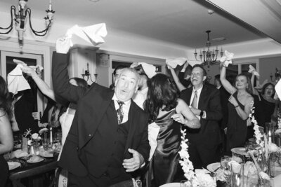 a black and white image of wedding guests twirling napkins to cheer on the newlyweds at a new jersey wedding venue