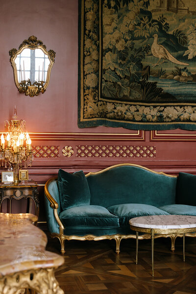 A close-up of a gold mirror and detailed wall decor in a French chateau, styled with vintage charm and luxury