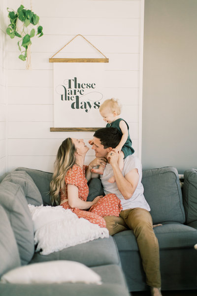 young family sitting on couch  during family portraits