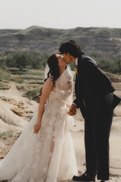 Wedding couple leaning in to kiss in the badlands of Alberta