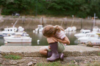 romantic ethereal portrait of little girl in purple wellies by the harbour