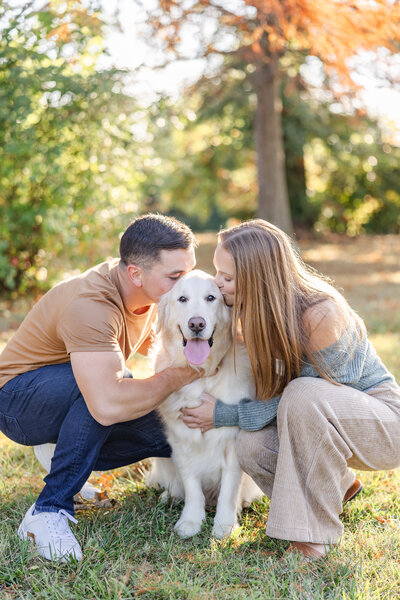 Couple kneeling and kissing their dog on the head while the dog pants and looks at the camera in Cincinnati, Ohio.