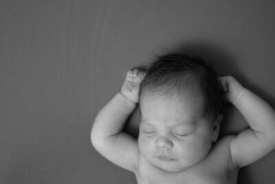 Newborn baby sleeping peacefully with one arm raised