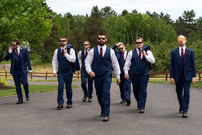Groom and wedding party walk down a path on wedding day.