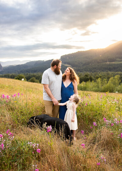 Family with black lab standing in wildflowers in the Columbia River Gorge.