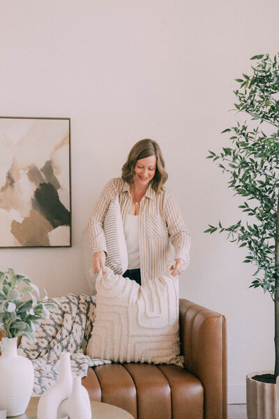 Bedroom staged by Modern Mollusk in Snohomish County featuring soft neutral bedding, wood furniture, and a round mirror accent.