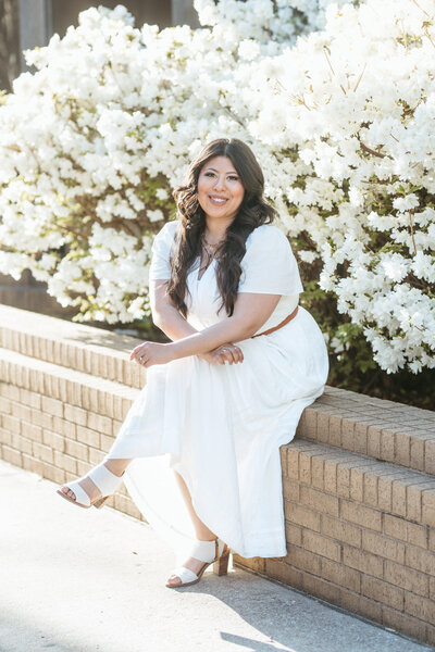 Portrait of Arkansas best wedding photographer at fayetteville square with white spring flowers behind her.