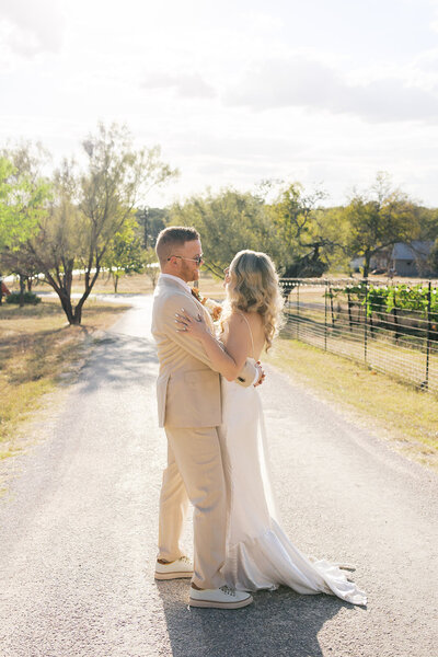 Bride and groom posing on a small road with trees in the background