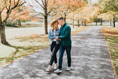 couple holding hands and walking on park path