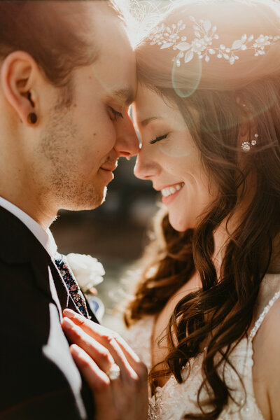 Wedding Couple forehead to forehead with a sun flare between their faces