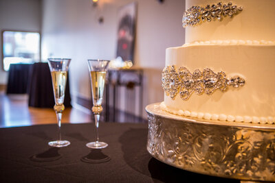 Gorgeous Wedding Cake On Silver Stand With Two Glasses Of Champagne