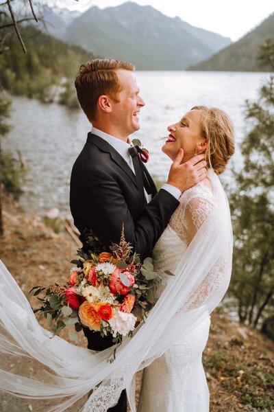 Montana bride and groom laugh near a lake