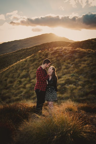 couple snuggling in the hills at sunset