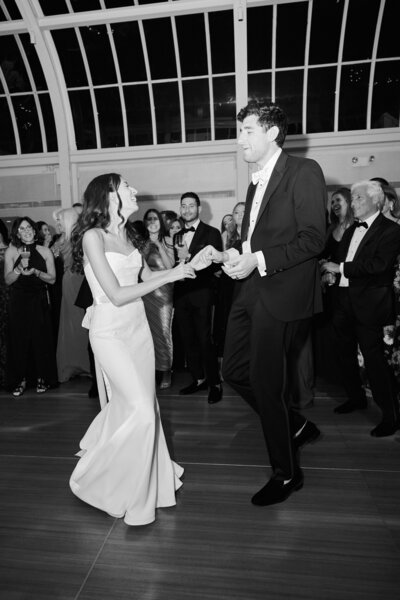 New York City Wedding at Brooklyn Botanical Garden Wedding Venue, where Bride and Groom Dance happily together as their guests look on.  Image taken by New York City Wedding Photographer, Corey Lamar Photography.  Wedding Photo taken in Black and white for artistic Effect.