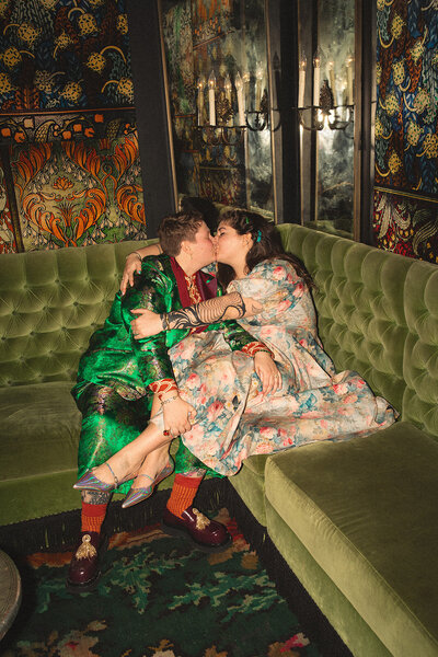 Los Angeles Engagement Party. Two brides kiss  on a green velvet sofa  at Petit Ermitage Hotel