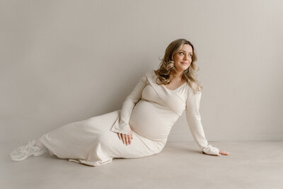 Zwangere vrouw in beige jurk in een studio