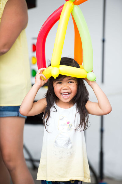 Ottawa Event Photography of a young girl smiling with a balloon crown on her head.  Captured during a corporate children's event by JEMMAN Photography COMMERCIAL