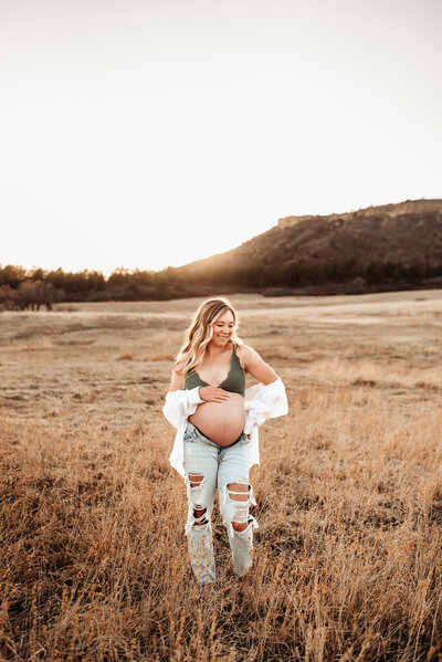 pregnant woman in bra and jeans in field