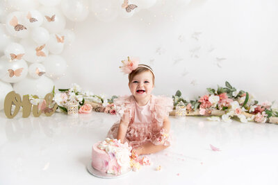 little girl wearing a pink butterfly dress and a pink crown for her Pink Butterfly Cake Smash photography session in Burlington, Ontario.