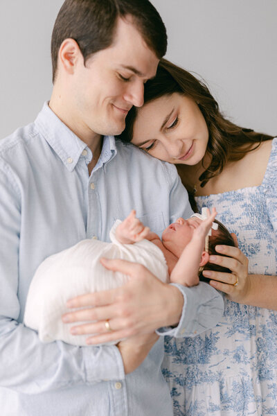 mom and dad holding newborn baby  in natural light wearing blue and white knoxville newborn photographer