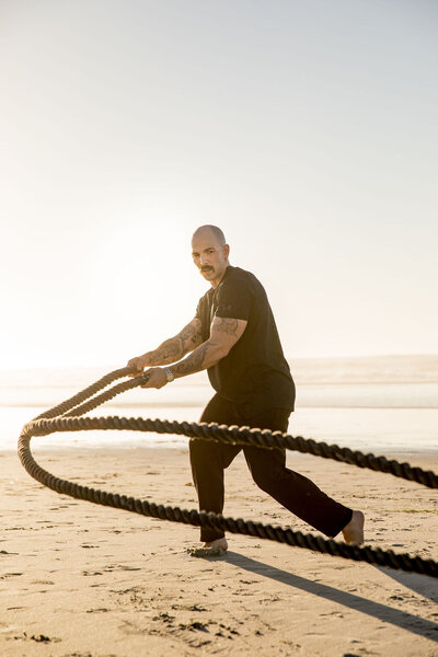 Scott of Iron and Salt Fitness doing a rope workout on the beach.